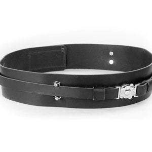 Puede incluir: Un cintur&oacute;n de cuero negro con hebilla plateada y tachuelas met&aacute;licas. El cintur&oacute;n es de doble capa y tiene un dise&ntilde;o sencillo.