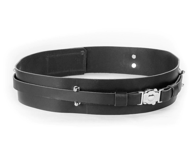 Puede incluir: Un cintur&oacute;n de cuero negro con hebilla plateada y tachuelas met&aacute;licas. El cintur&oacute;n es de doble capa y tiene un dise&ntilde;o sencillo.