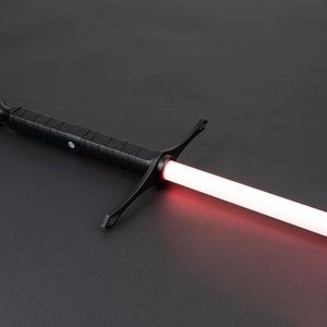 May include: A black lightsaber with a red blade. The lightsaber has a black handle with a textured grip and a crossguard.