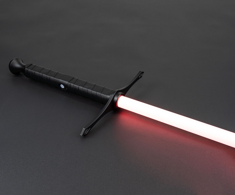 May include: A black lightsaber with a red blade. The lightsaber has a black handle with a textured grip and a crossguard.