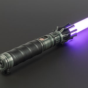 K&ouml;nnte beinhalten: Ein schwarzes Lichtschwert mit einer violetten Klinge. Das Lichtschwert hat einen strukturierten Griff und eine silberne Akzentuierung in der N&auml;he der Klinge.