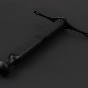 May include: A black, tactical-style sword with a textured grip and a cross-shaped guard. The sword is made of metal and has a sharp point.