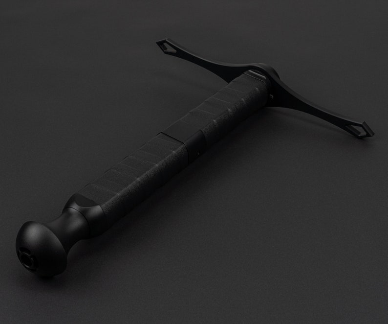 May include: A black, tactical-style sword with a textured grip and a cross-shaped guard. The sword is made of metal and has a sharp point.