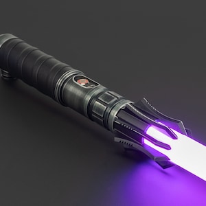 K&ouml;nnte beinhalten: Ein schwarzes Lichtschwert mit einer violetten Klinge. Das Lichtschwert hat einen strukturierten schwarzen Griff mit einem silbernen Akzent und einen schwarzen Emitter mit einem silbernen Ring.