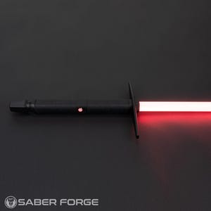 May include: A black lightsaber with a red blade. The lightsaber is turned on and the blade is glowing. The lightsaber is on a black surface.