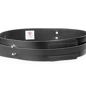 Puede incluir: Cintur&oacute;n de cuero negro con dos correas y tachuelas plateadas. El cintur&oacute;n tiene un peque&ntilde;o bolsillo rectangular en la parte delantera. La etiqueta dice "Cuero hecho a mano".