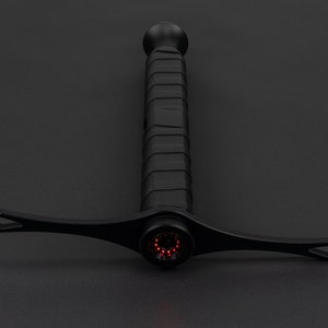 May include: A black sword with a red light at the tip. The sword has a textured handle.