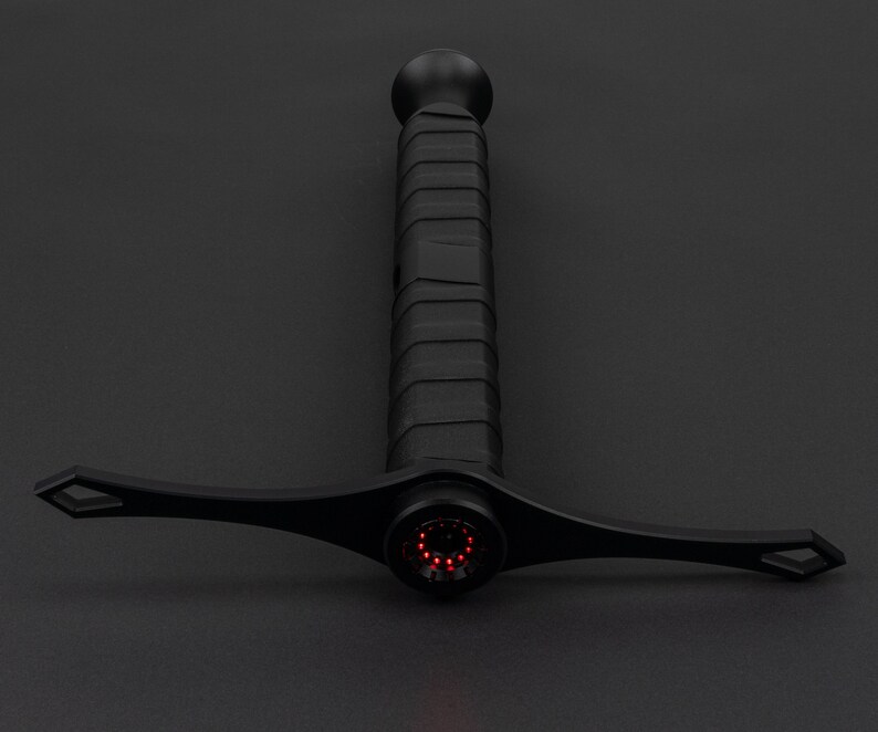 May include: A black sword with a red light at the tip. The sword has a textured handle.