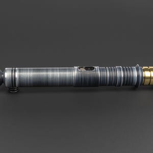 Puede incluir: Un sable de luz plateado con un acento dorado en el mango.