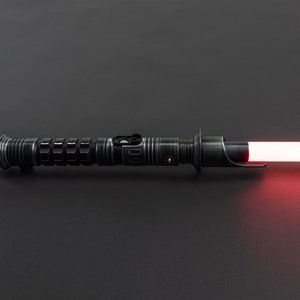 K&ouml;nnte beinhalten: Ein schwarzes Lichtschwert mit einer roten Klinge. Das Lichtschwert hat einen strukturierten Griff und einen silbernen Akzent.