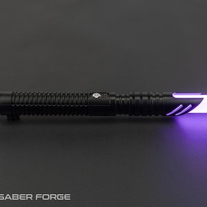 May include: A black lightsaber with a ribbed handle and a glowing purple blade. The hilt features a button and a logo. The lightsaber is set against a dark gray background. The Saber Forge logo is at the bottom.
