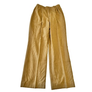 May include: A pair of tan-colored wide-leg pants. The pants have a button and zipper closure, pleats at the waist, and a classic, tailored design. The fabric appears to be a woven material.