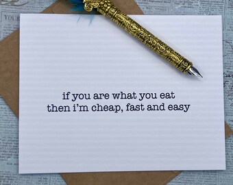 May include: A white card with black text that reads "if you are what you eat then i'm cheap, fast and easy". A gold pen with a blue feather is lying on top of the card.