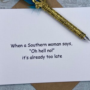 May include: A white card with black text that reads "When a Southern woman says, "Oh hell no!" it's already too late". A gold pen with a blue feather is on top of the card.