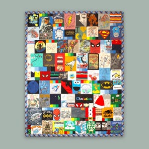 May include: A colourful quilt made from a variety of t-shirts featuring cartoon characters, logos, and text. The quilt is made up of squares of different colours and patterns, and is bordered with a blue and white checked fabric.