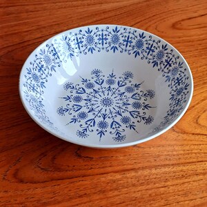 Peut inclure: Un bol en céramique blanche avec un motif floral bleu et blanc. Le bol présente un motif de flocon de neige au centre et une bordure de motifs floraux plus petits autour du bord.