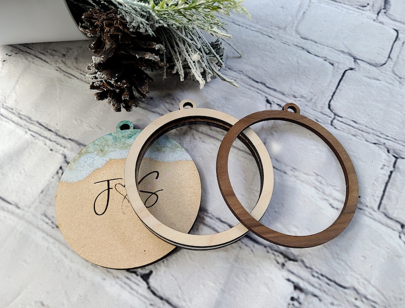 May include: Three unfinished wooden ornaments, two are round and one is round with a painted design. The round ornaments have a hole at the top for hanging. The painted ornament has the letters "J & S" written on it.