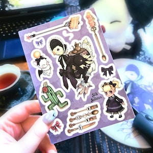 May include: A sticker sheet with various whimsical illustrations on a purple background. Designs include a bird-like figure in a maid outfit, a cactus, and decorative spoons. The text "Silk Sutures" is also present.