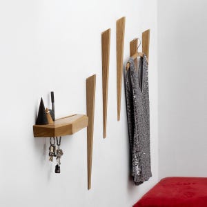 May include: A wooden wall-mounted shelf with a geometric design and a set of four wooden hooks. The shelf has a small ledge for storing keys or other small items. A silver sequined top is hanging on one of the hooks.