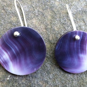 May include: A pair of earrings with purple and white shell discs and silver hooks.