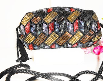 May include: A small, beaded evening bag with a black cord strap and tassel. The bag is decorated with a geometric pattern of gold, red, and blue beads.