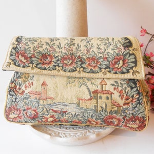 May include: A vintage tapestry clutch bag with a floral and landscape design. The bag is beige with red, green, and blue accents.