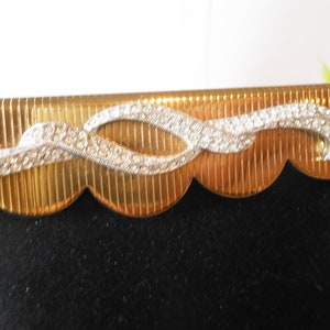 May include: Gold picture frame with a scalloped edge and a decorative rhinestone design.