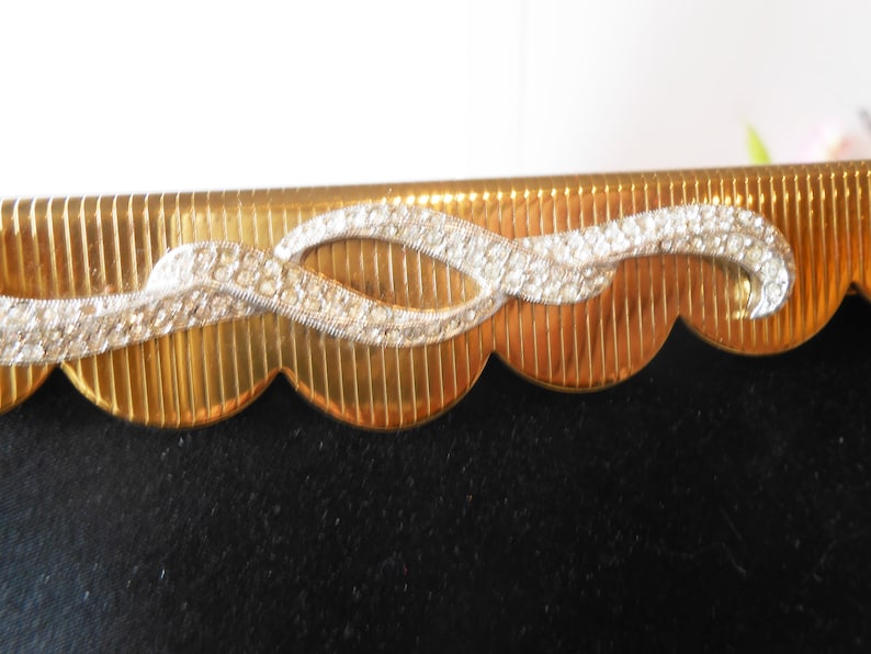 May include: Gold picture frame with a scalloped edge and a decorative rhinestone design.