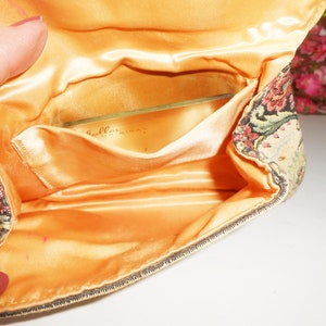 May include: A vintage tapestry fabric clutch purse with a satin lining and a clear plastic pocket. The pocket has the text "Bellissima" printed on it.