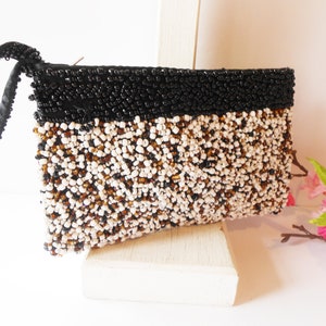 May include: A small black and white beaded clutch bag with a black satin strap.
