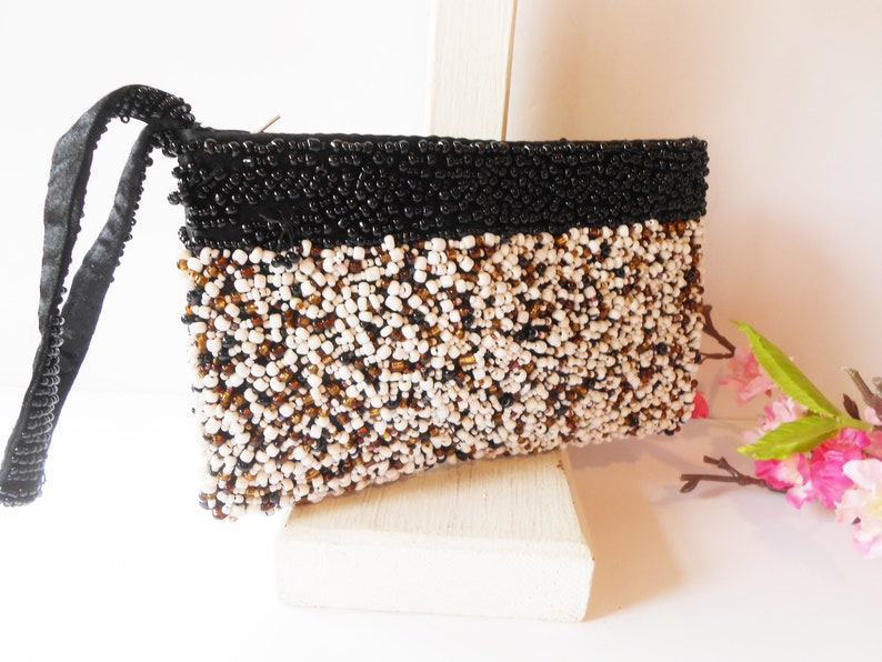 May include: A small black and white beaded clutch bag with a black satin strap.