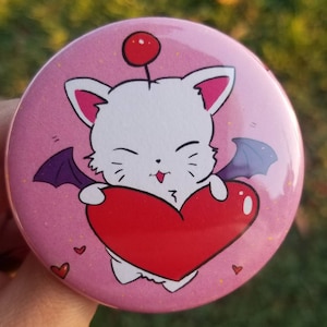 May include: A pink button with a white cartoon character holding a red heart. The character has purple wings and a red cherry on top of its head.