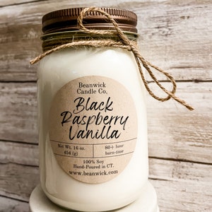 May include: A large, clear glass jar candle with a bronze lid and a twine bow. The candle has a label that reads "Black Raspberry Vanilla" and "Net Wt. 16 oz. 454 (g)". The candle is hand-poured in CT and made of 100% soy.