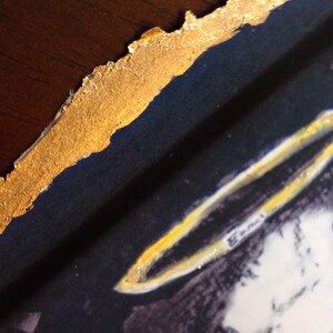 May include: A close-up of a painting with a gold border. The painting depicts a person with a halo above their head. The halo is made of gold and has a sparkly texture.