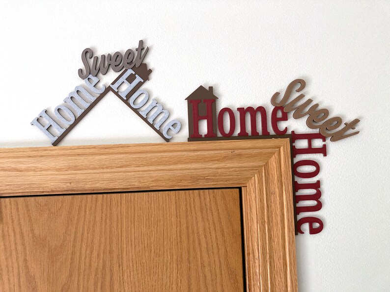 comparing the new larger home sweet home door decoration with the regular sized one on a door frame