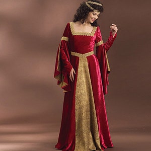 May include: A red velvet gown with gold trim and long sleeves. The gown has a fitted bodice and a flowing skirt. The model is wearing a gold crown.