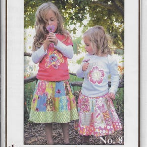 Puede incluir: Dos niñas con faldas y camisetas de patchwork. La niña de la izquierda lleva una camiseta rosa con un diseño floral y una falda de patchwork multicolor. La niña de la derecha lleva una camiseta blanca con un diseño de flor rosa y una falda de patchwork rosa y blanca. La imagen es de Pink Fig Patterns y se titula "The Patchwork Skirt & T-Shirt" No. 8.