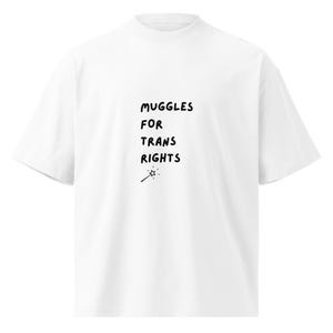 Pode incluir: Camiseta branca com texto preto que diz "MUGGLES FOR TRANS RIGHTS" e um pequeno desenho de uma varinha mágica com uma estrela no final.