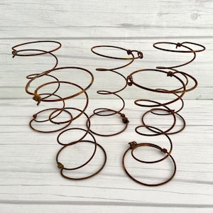 May include: Four rusty metal bed springs, each with multiple coils, are arranged on a white wooden surface. The springs are a popular rustic decor item.