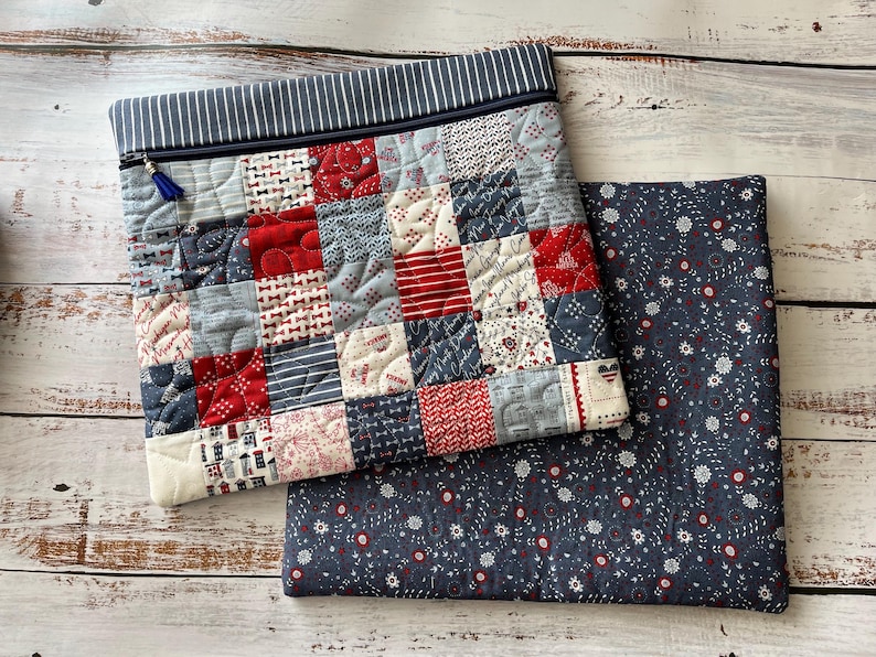 Puede incluir: Un estuche acolchado con cremallera que presenta un dise&ntilde;o de patchwork de cuadrados de tela rojos, blancos y azules con varios patrones, rematado con un borde a rayas azul marino y blanco y una borla azul, junto a una pieza de tela azul oscuro.