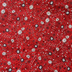 May include: Red fabric with a repeating floral pattern. The design features white and gray flowers, small stars, and delicate stems with tiny leaves. The background is a solid, vibrant red.