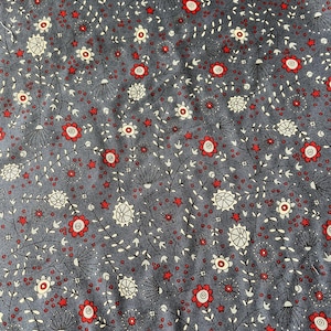 Puede incluir: Una tela gris oscuro con un patr&oacute;n repetitivo de peque&ntilde;as flores rojas, motivos florales circulares blancos y diminutas estrellas rojas. El dise&ntilde;o incluye tallos y hojas negras finas que conectan los elementos florales.