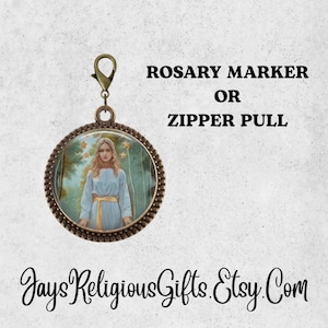 May include: A round, bronze-colored charm with a clasp, featuring an image of a woman in a blue robe. The charm is labeled "Rosary Marker or Zipper Pull". The background is a light, textured surface.