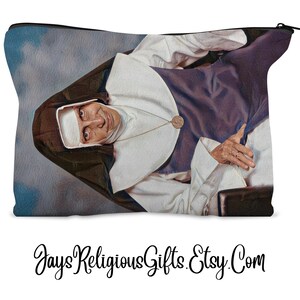 May include: A rectangular zippered pouch featuring a portrait of a nun in a white habit and a dark brown veil. The nun is wearing a gold-colored necklace. The background is a cloudy sky. The text "JaysReligiousGifts.Etsy.Com" is at the bottom.