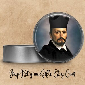 May include: A round, silver tin with a clear lid. The lid features a colorful image of a man wearing a black hat and robe. The text "Jays Religious Gifts. Etsy.Com" is printed on the bottom of the tin.