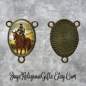 May include: A bronze oval-shaped pendant with a religious image of a man on horseback. The pendant has a decorative design on the back.