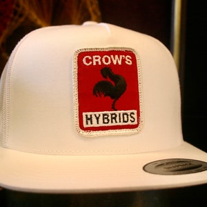 May include: White trucker hat with a red and white patch that says "CROW'S HYBRIDS" and features a black rooster silhouette.