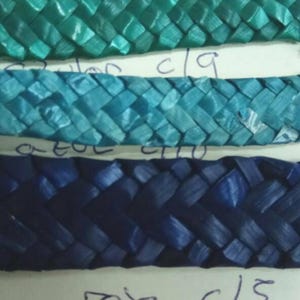 May include: Close-up of four woven strips of material in different colors. The strips are labeled "verde c18", "azul c19", "roxa c15", and "rosa c15".