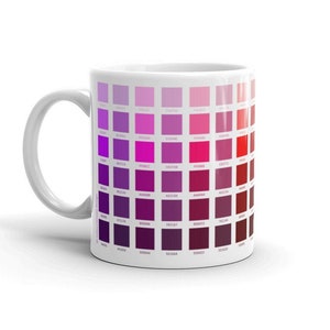 May include: White ceramic mug with a color chart printed on the side. The chart features a gradient of purple and red shades, with each color represented by a small square. The squares are arranged in rows and columns, creating a visual representation of the color spectrum.