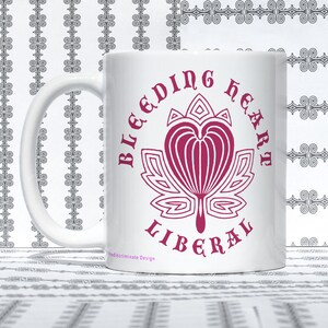 May include: White ceramic mug with a pink graphic of a stylized bleeding heart with the text "Bleeding Heart Liberal" around it. The text "Indiscriminate Design" is at the bottom of the mug.